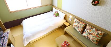 A small, neatly arranged room with a bed, a bench, and a small table.