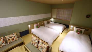 A hotel room with two beds, a sofa, and a small table.