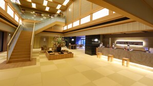 Un hall d’entrée spacieux avec un escalier, un coin salon et un comptoir d’accueil.