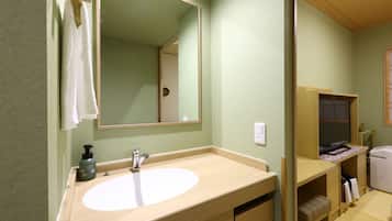 Une salle de bain avec un meuble-lavabo en bois, un grand miroir, un lavabo et un porte-serviettes.