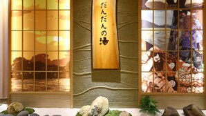 Un intérieur japonais traditionnel avec un panneau en bois orné de caractères japonais, un paravent décoratif représentant un paysage et un petit jardin de pierres en bas.