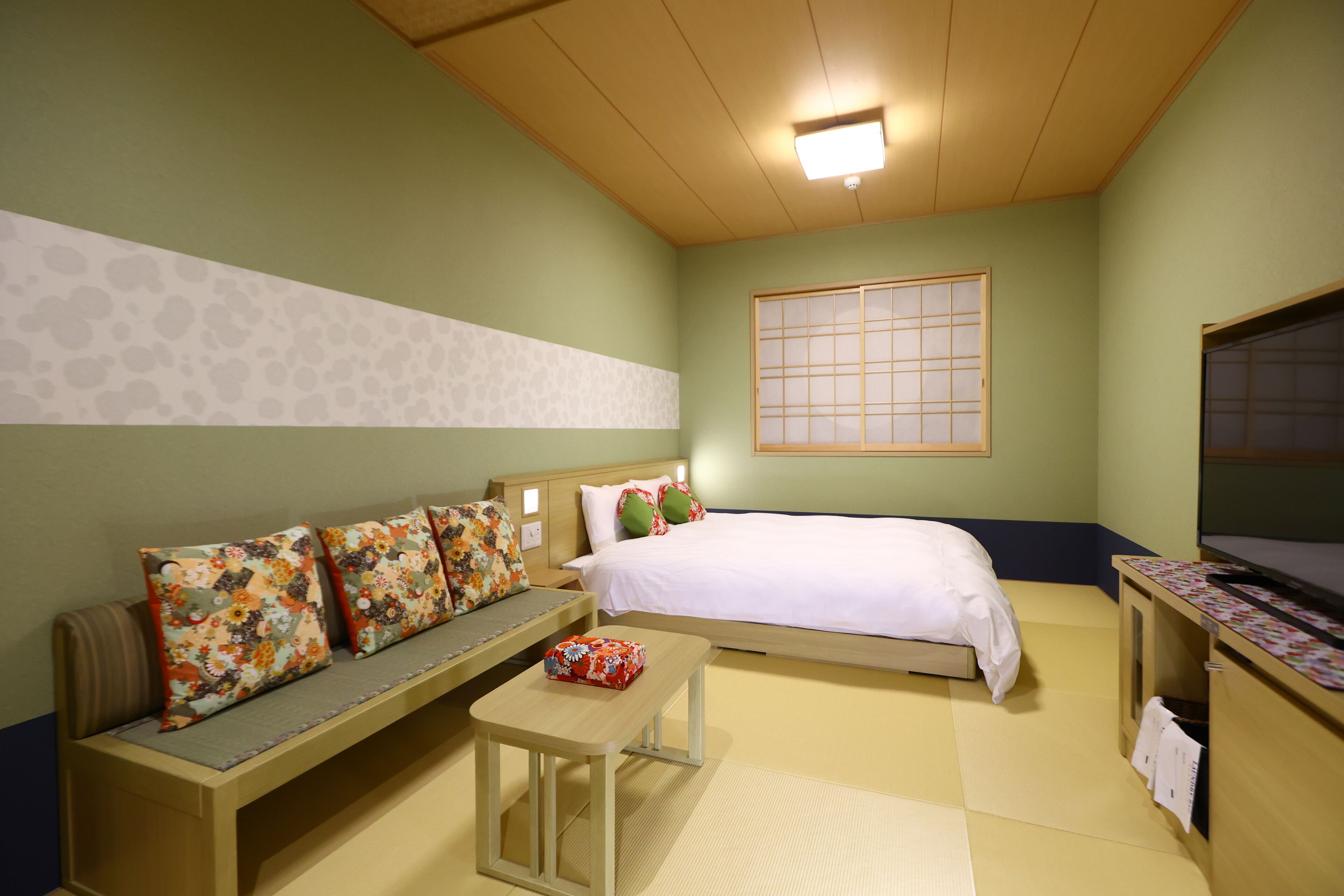 A room with a bed, a bench, a small table, and a window with a view.