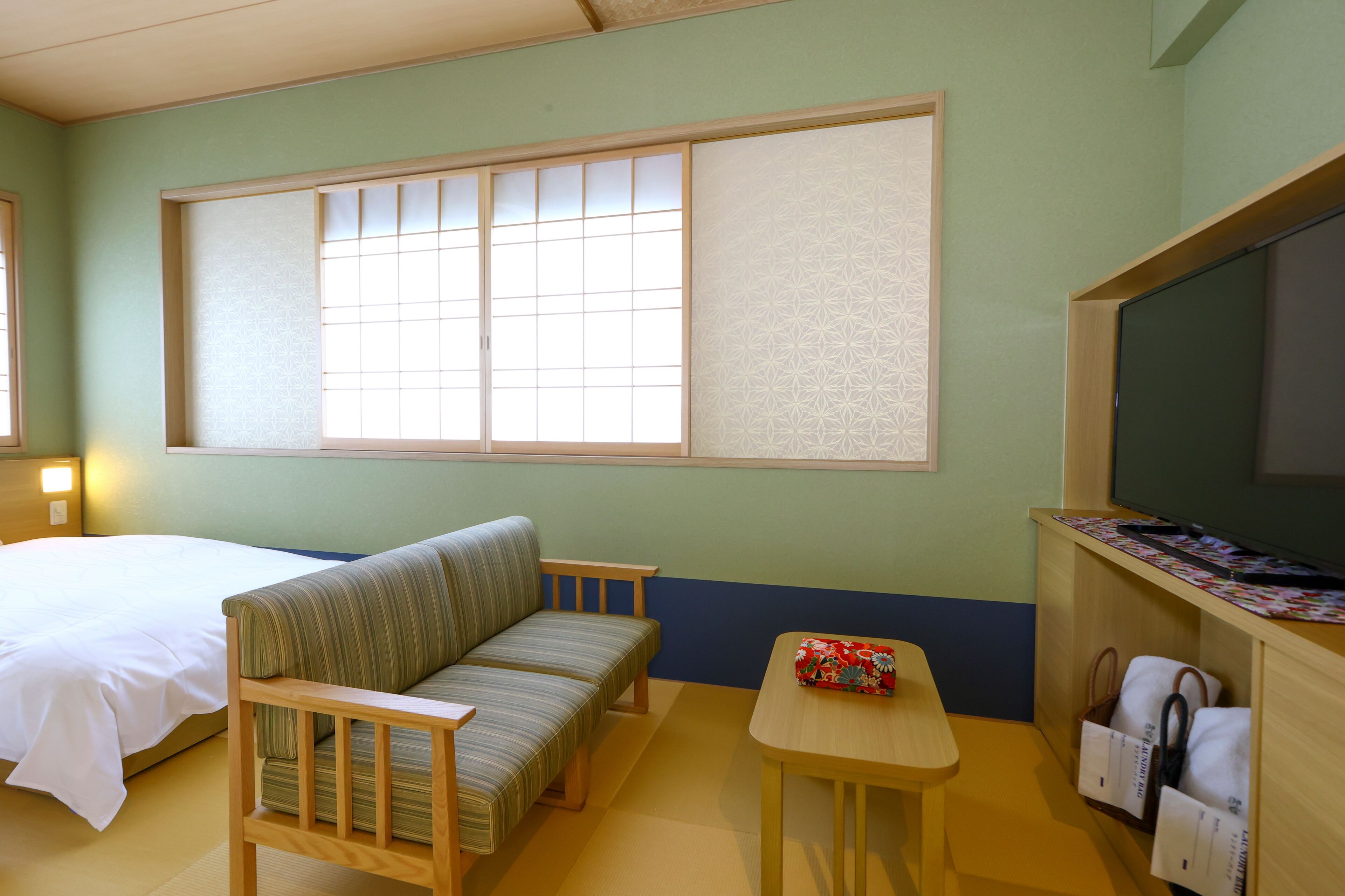 A room with a bed, a sofa, a small table, and a TV.