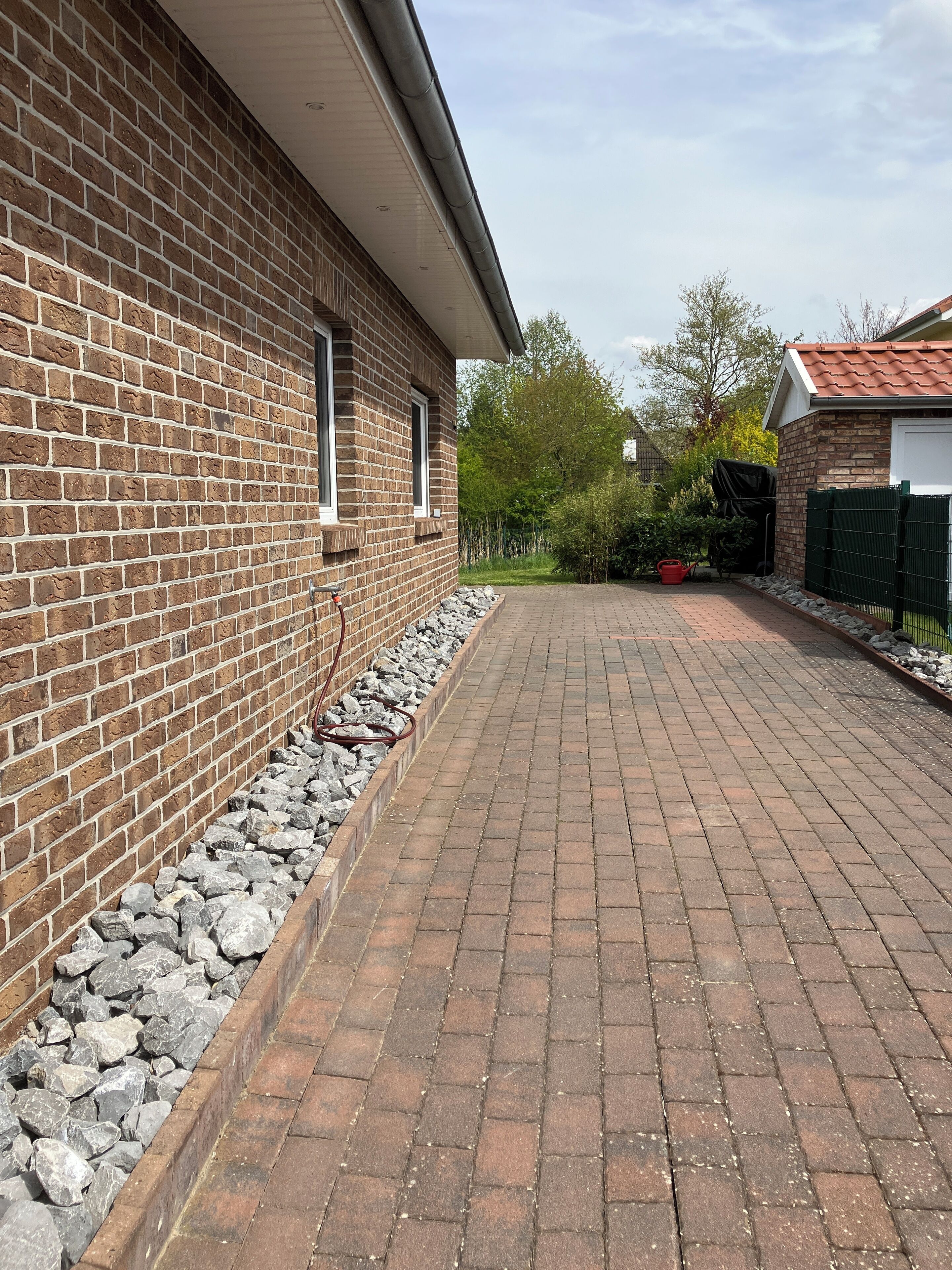 A brick building with a paved driveway and a stone border.
