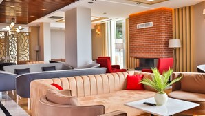 A modern hotel lobby with a seating area featuring sofas and armchairs, a small table with a plant, and a brick accent wall. - The Sign Degirmen Hotel & Spa (Sile)