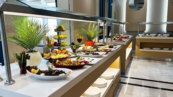 Un buffet proposant une variété de plats et une présentation de fruits.