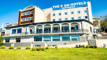 A hotel with a prominent sign, multiple balconies, and a well-maintained lawn.
