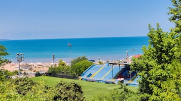 A stadium with blue seating and a view of the sea.