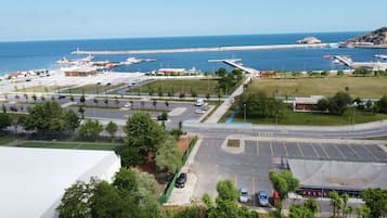 Vista aérea de un puerto deportivo costero con barcos amarrados, un estacionamiento y una carretera que conduce al puerto.