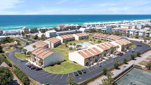 Un resort costero con edificios de varios pisos, un estacionamiento y una zona de piscina.
