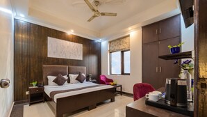 A hotel room with a bed, bedside table, nightstand, wardrobe, and a desk with a coffee maker. - Hotel Diamond Stay by ASPL (Noida)