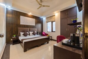 A hotel room with a bed, bedside table, nightstand, wardrobe, and a desk with a coffee maker. - Hotel Diamond Stay by ASPL (Noida)