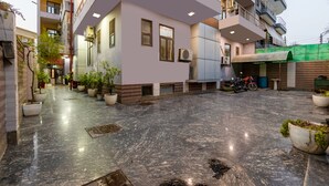 A multi-story building with a courtyard, potted plants, and parked motorcycles. - Hotel Diamond Stay by ASPL (Noida)