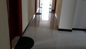 A corridor with a shiny tiled floor and wooden doors. - 20/20 Guest House (Addis Ababa)