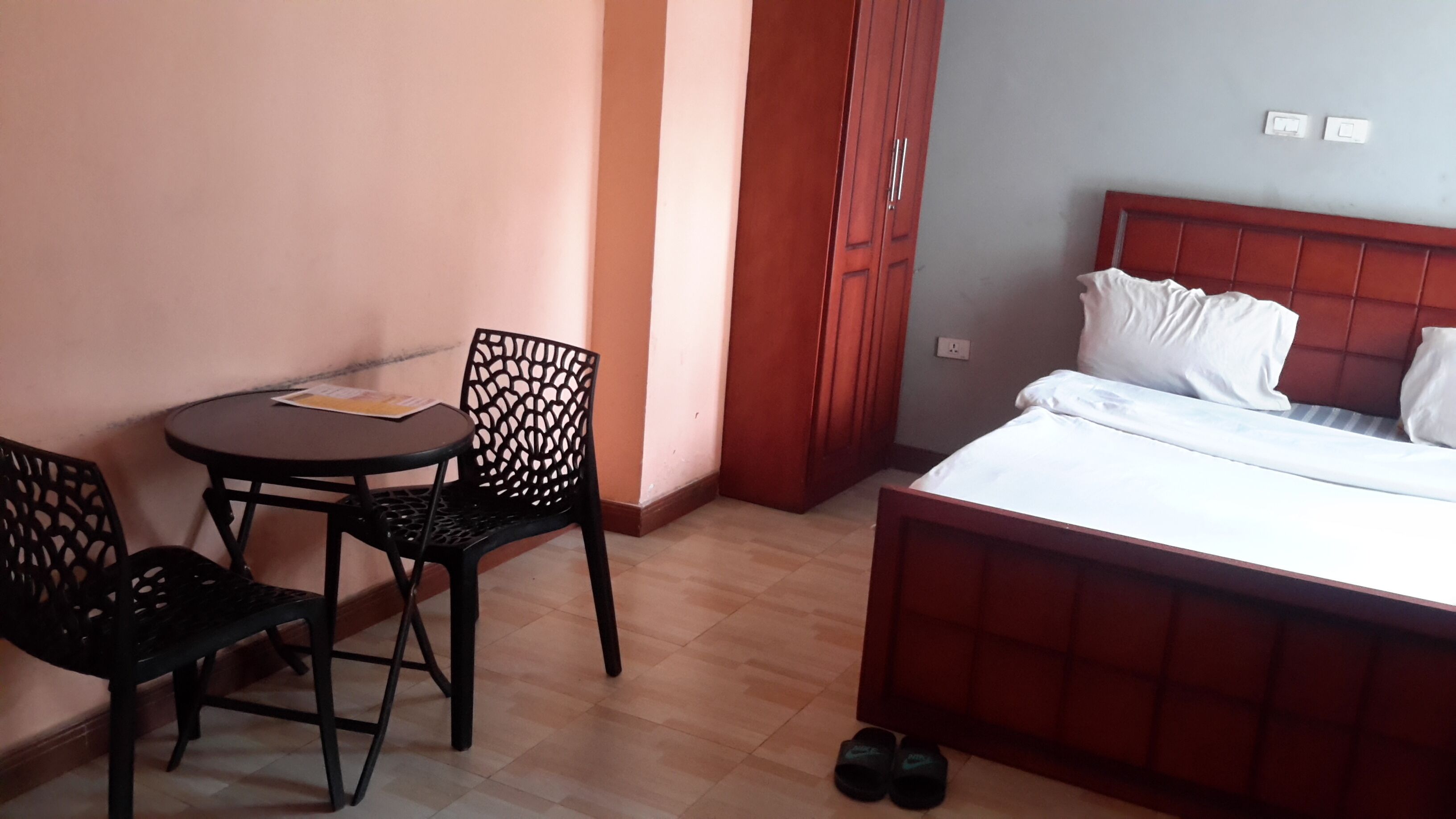 A hotel room with a bed, two chairs, a small table, and a door.