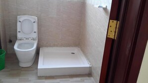 A small, clean bathroom with a white toilet and a shower stall. - 20/20 Guest House (Addis Ababa)