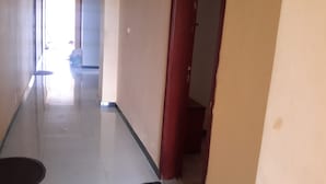 A hallway with a tiled floor, a door on the right, and a window at the end. - 20/20 Guest House (Addis Ababa)