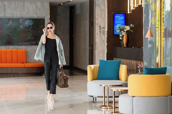 A modern lobby with a seating area, a digital display, and a decorative vase.