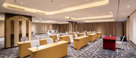 A conference room with multiple tables and chairs, a red table, and a projector screen.