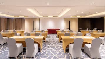 A conference room with tables and chairs, a podium, and a carpeted floor.