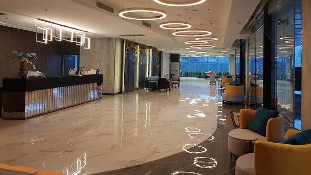 A modern lobby with a reception desk, seating area, and large windows offering a view. - Best Western Nada Don Mueang Airport Hotel (Bangkok)