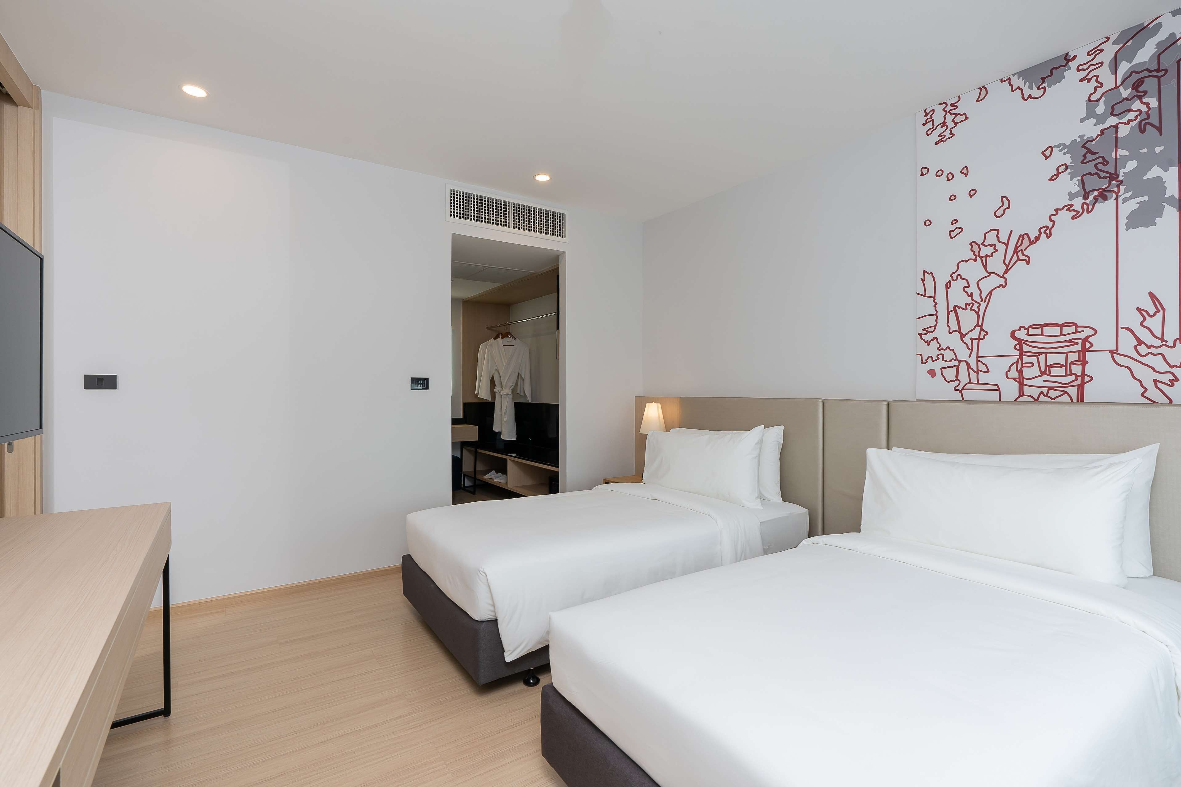 Een hotelkamer met twee bedden, een bureau en een kledingkast.