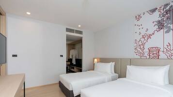 Een hotelkamer met twee bedden, een bureau en een kledingkast.