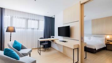 A modern hotel room with a desk, chair, television, bed, and a large mirror.