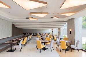 A spacious restaurant with high ceilings, modern pendant lighting, and a mix of yellow and white chairs. - Best Western Nada Don Mueang Airport Hotel (Bangkok)