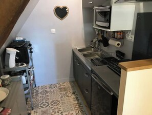 A compact kitchen with a microwave, sink, and a heart-shaped decoration on the wall.