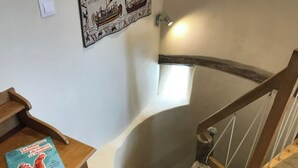 Un escalier avec une rampe en bois et un luminaire fixé au mur.