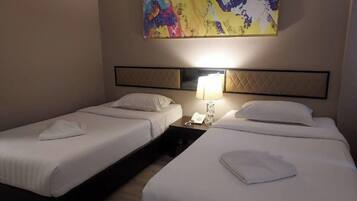 A hotel room with two beds, a nightstand with a lamp, and a colorful abstract painting on the wall.