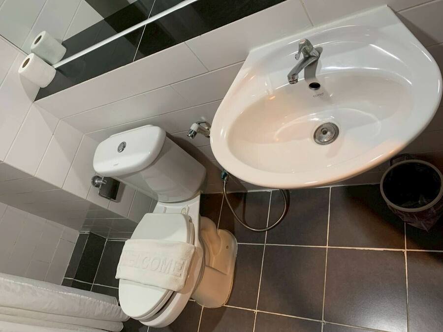 A bathroom with a toilet, sink, and a towel with 'WELCOME' written on it.