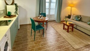 Ein gemütliches Wohnzimmer mit Essbereich, einer Couch, einer Lampe und einer Küchenzeile inklusive Waschmaschine.