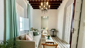 Ein Wohnzimmer mit Sofa, Sesseln, einem Tisch und einer Chandelüster.