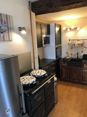 A compact kitchen with a refrigerator, stove, microwave, and wooden cabinets.