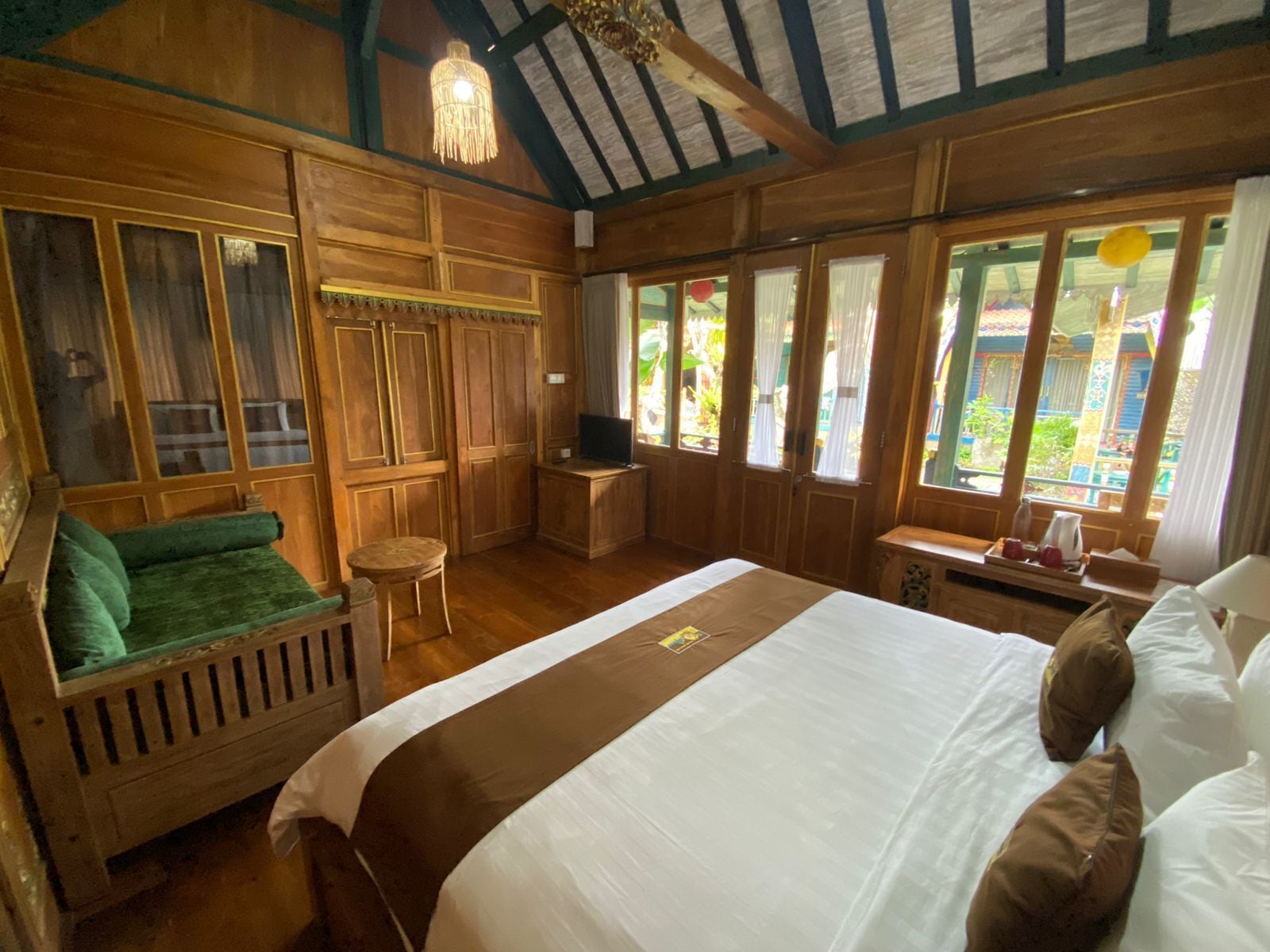 Une pièce en bois avec un grand lit, un petit coin salon et un téléviseur.