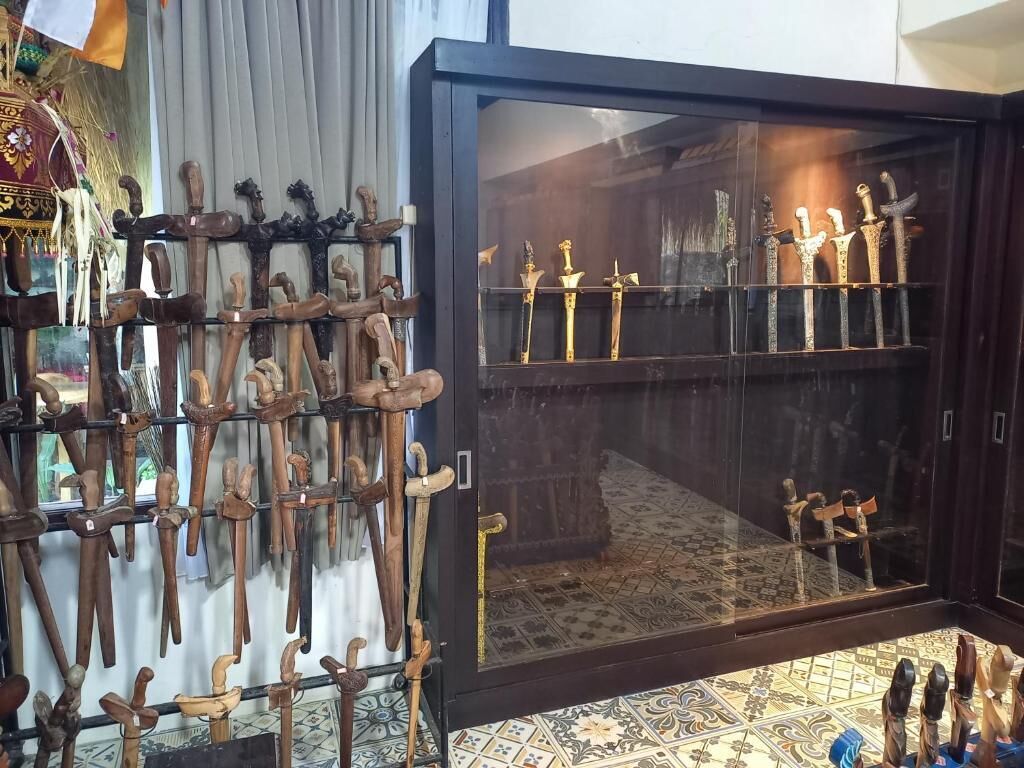 A display of wooden walking sticks and swords in a glass case.