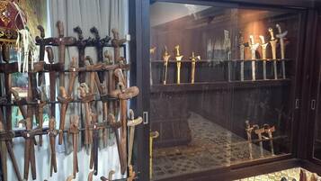 A display of wooden walking sticks and swords in a glass case.