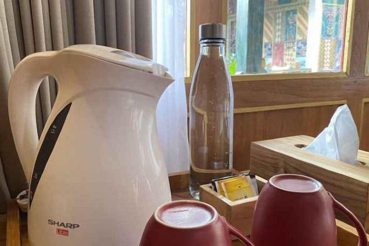 A room with a white electric kettle, a clear bottle, and a red cup on a wooden table.