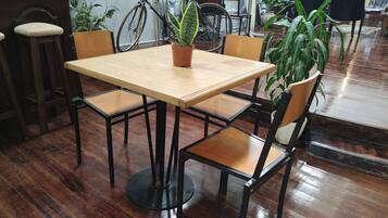 Una mesa de madera con cuatro sillas, una planta en maceta y una bicicleta en una habitación con suelo de madera y sillas.