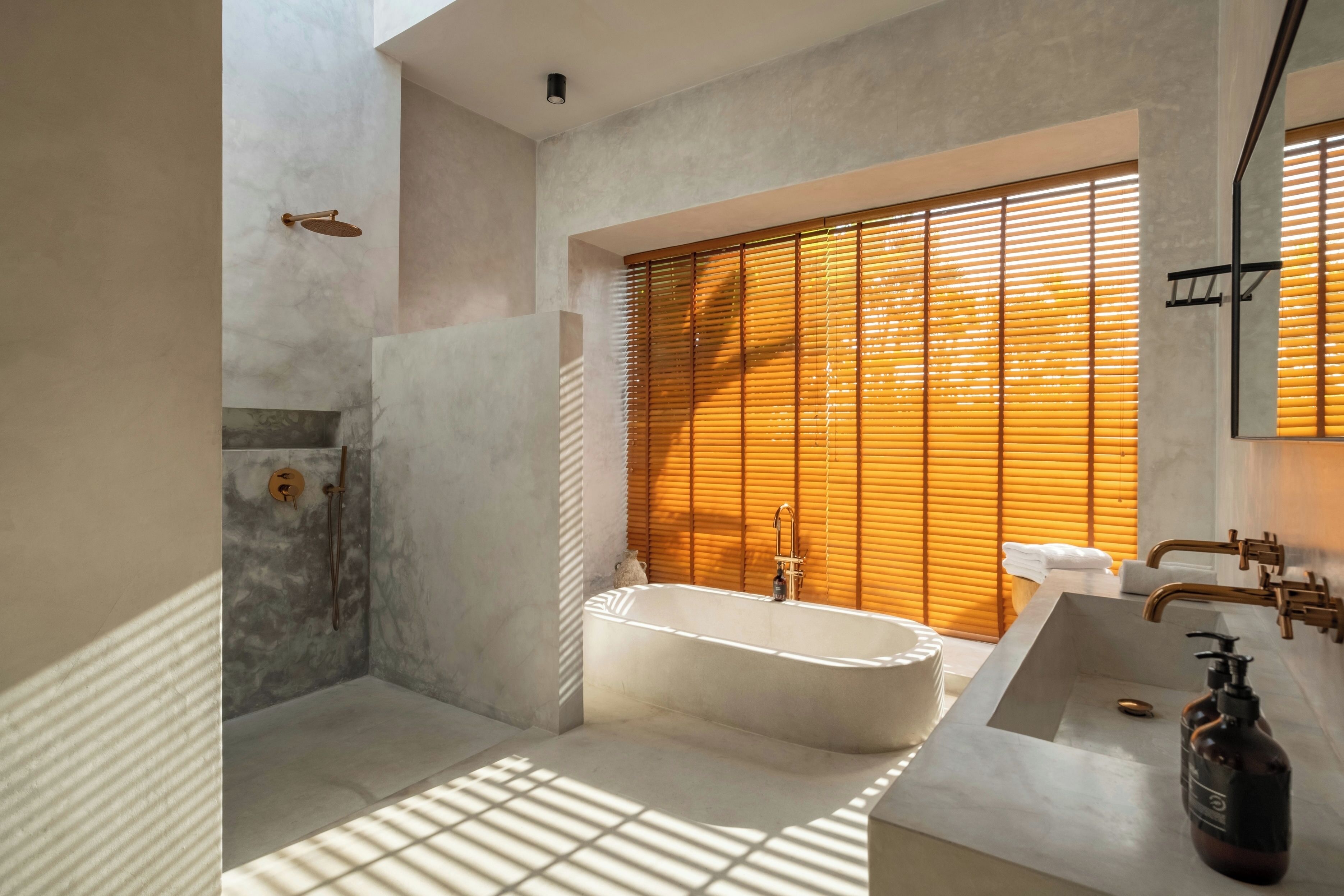 Un baño moderno con una bañera independiente, zona de ducha y lavabo con dispensador de jabón.