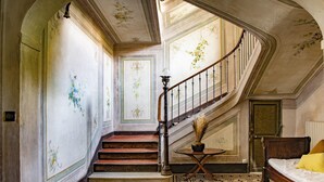 Eine imposante Treppe mit aufwendigen Wandverzierungen, einem gemusterten Boden und einer gemütlichen Sitzecke mit Bett und Lampe.