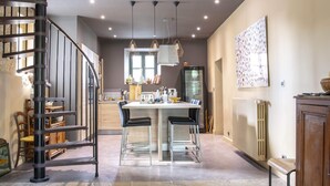 Een moderne keuken met een centraal eiland, een spiraaltrap en een eethoek met barstoelen.