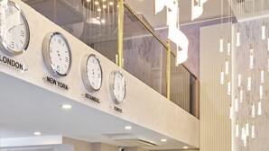 A hotel reception area with a marble reception desk, clocks displaying times from London, New York, Istanbul, and Tokyo, and a modern chandelier. - actuel life hotel (Istanbul)