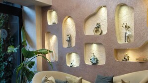 Een moderne woonkamer met een beige bank, een ronde salontafel en decoratieve wandnissen met sculpturen.