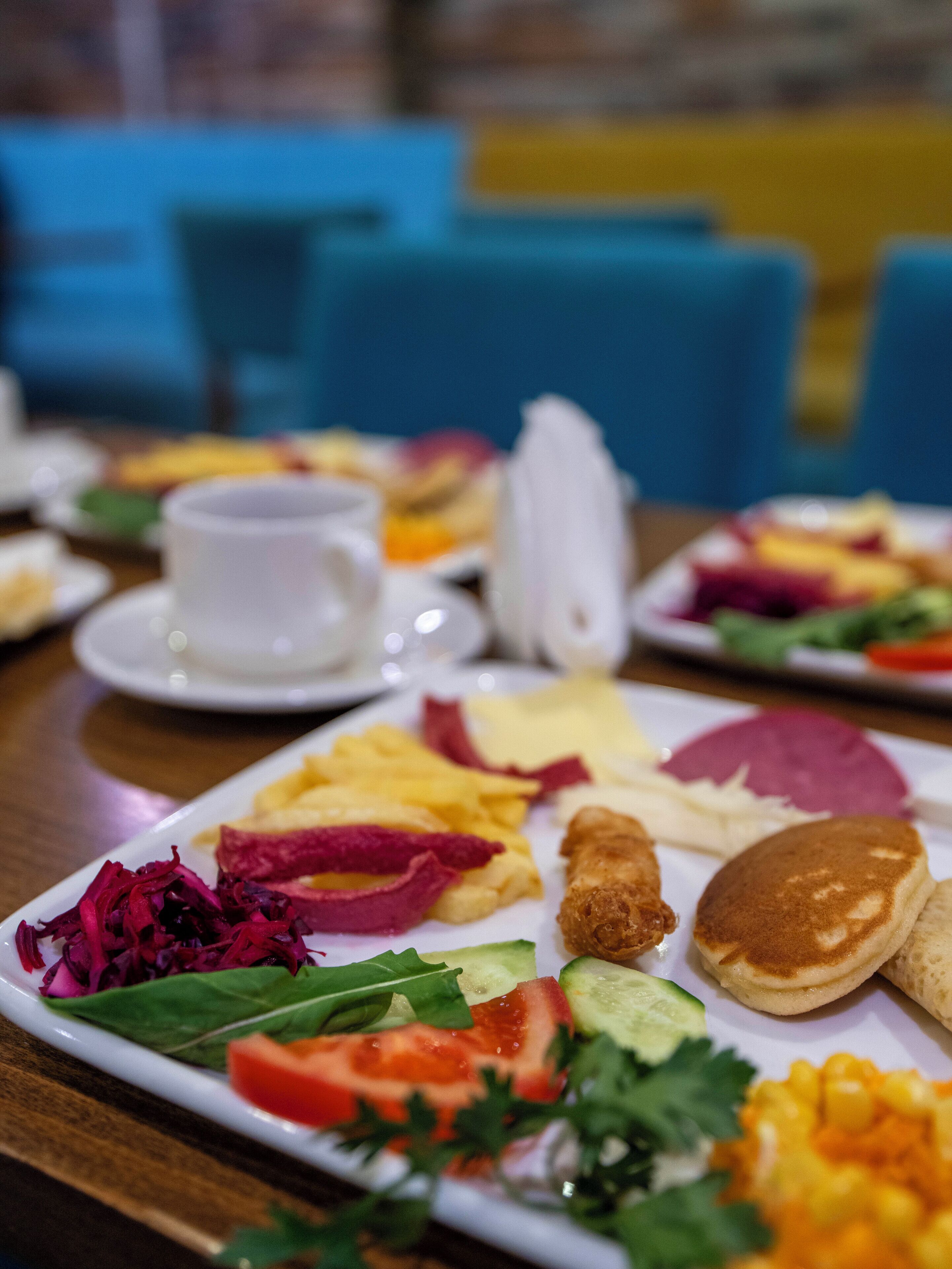 Een ontbijtbuffet met diverse gerechten, waaronder pannenkoeken, eieren en groenten.