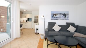 A modern living room with a grey sofa, a coffee table, and a painting of a snowy landscape.