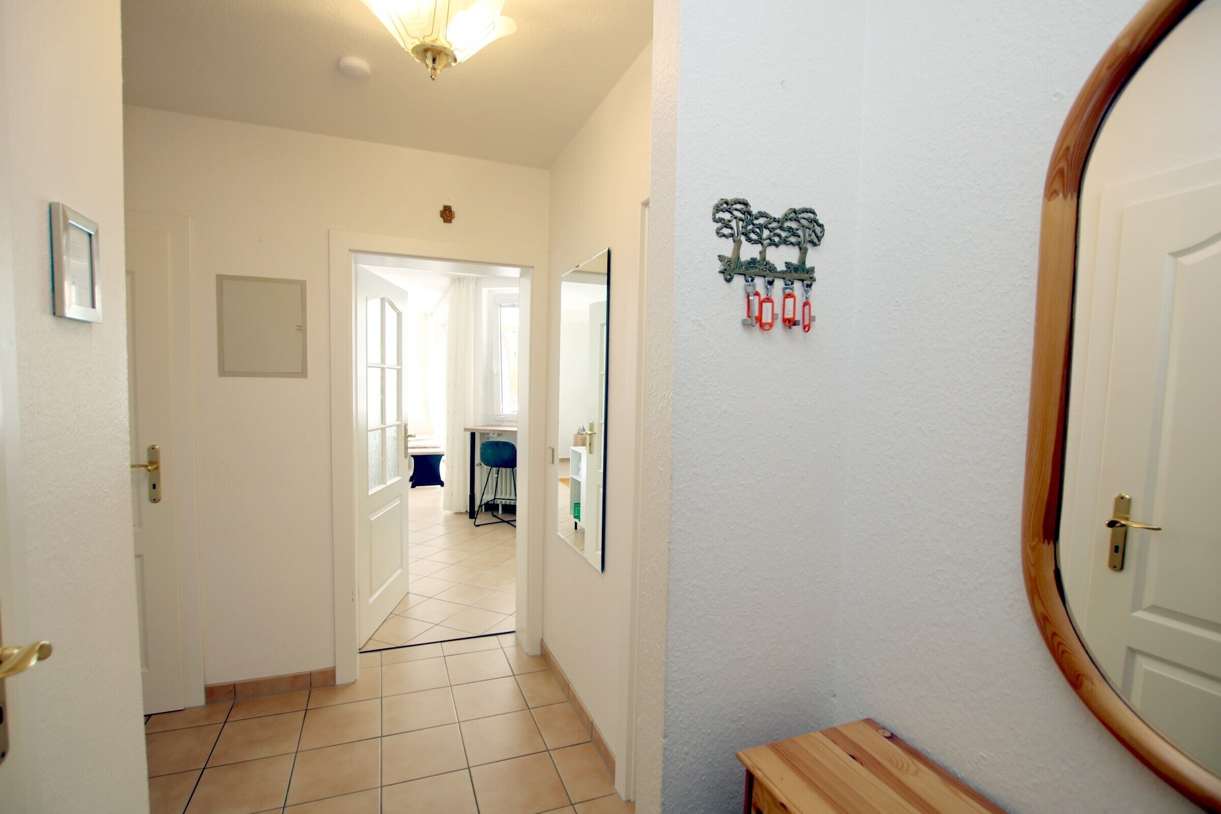 A hallway with a wooden bench, a mirror, and a wall-mounted decoration.