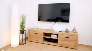 A wooden TV stand with a flat-screen TV mounted on the wall above it.
